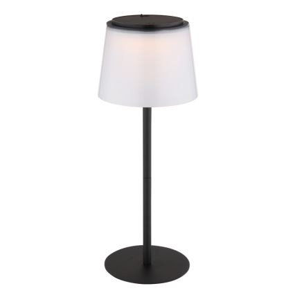 Stojacia lampa svieti. Má čierny kovový stojan a biely tienidlo. Je umiestnená na bielom pozadí.