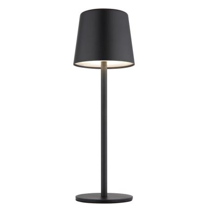 Čierna stolová lampa s kužeľovitým tienidlom svieti. Má vysokú, úzku nohu a kruhovú základňu. Je umiestnená na bielom pozadí.