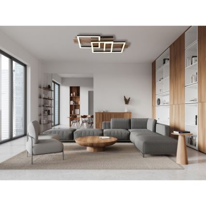 Svietidlo svieti v modernej obývacej izbe. Svietidlo je tvorené prepletenými štvorcami z dreva a svetla. Izba obsahuje sedaciu súpravu, konferenčný stolík a knižnice.