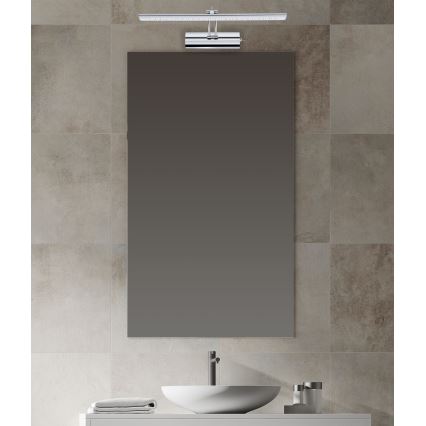 Svetlo nad zrkadlom svieti v kúpeľni. Zrkadlo je obdĺžnikové, umiestnené nad umývadlom. Kúpeľňa má dlaždicovú stenu.