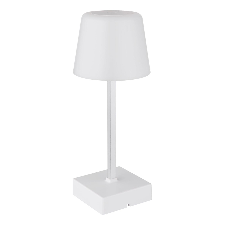 Biela stolová lampa s valcovým tienidlom a štíhlym stĺpikom stojí na bielej štvorcovej podstave. Lampa je osvetľovacím zariadením na stole. Pozadie je biele.
