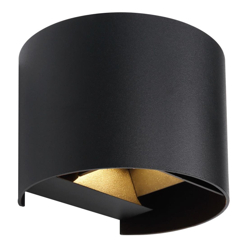 Čierna nástenná lampa s valcovým tienidlom svieti. Vnútorný zlatý prvok odráža svetlo. Lampa je umiestnená na bielom pozadí.