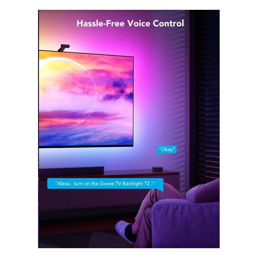 Televízor s podsvietením LED pásikom je ovládaný hlasom prostredníctvom Alexy. Muž sedí na pohovke v obývačke. Hlasový príkaz je „Alexa, zapni podsvietenie Govee TV Backlight T2.“ Odpoveď je „Okay“.
