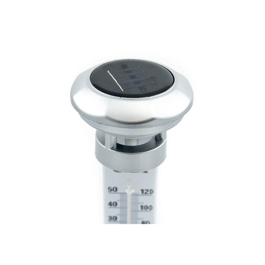 Solárny teplomer meria teplotu. Strieborné puzdro s tmavosivým solárnym panelom. Teplotná stupnica v °C a °F.