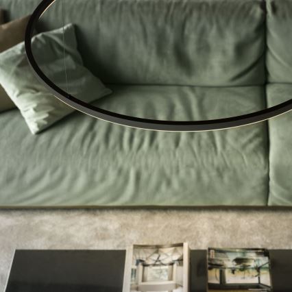 Kruhové svietidlo visí nad zelenou sedačkou. Pod svietidlom sa nachádza nízky stolík s časopismi.