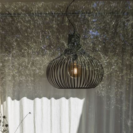 Svietidlo visí zo stropu. Je kovové, tmavej farby, s okrúhlym tienidlom zloženým z prepletených prúžkov, vnútri je žiarovka. Svietidlo je pred svetlým závesom, na ktorý sa premieta tieň stromov z vonku.