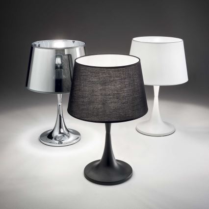 Tri stolové lampy stoja na svetlej ploche. Stredná lampa má čierny tienidlo a čierny podstavec. Lampy vľavo a vpravo majú strieborný a biely tienidlo a podstavec.