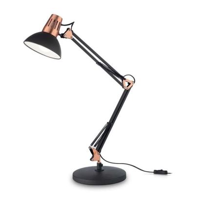 Stolová lampa s čiernym tienidlom a medenými prvkami stojí na čiernej podstave. Lampa je na dlhom, pohyblivom ramene. Elektrický kábel je pripojený k spodnej časti.