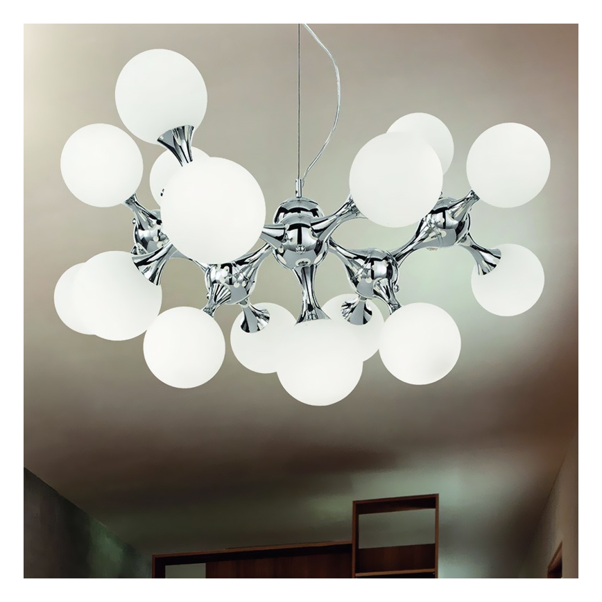 Stropné svietidlo s viacerými guľatými tienidlami z matného skla visí z chrómového držiaka v tvare rozvetveného stromu. Svietidlo je umiestnené v interiéri, na strope miestnosti s nábytkom.