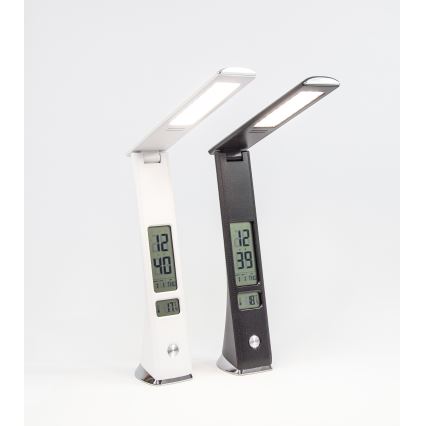 Dve stolové lampy s LED osvetlením a digitálnym displejom zobrazujúcim čas a teplotu stoja na bielom povrchu. Lampa vľavo je biela, vpravo čierna. Obe lampy sú sklopené.