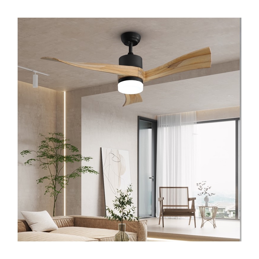 Drevený stropný ventilátor s osvetlením rotuje v modernom interiéri obývacej izby. Ventilátor má drevené lopatky a čierny kovový stred. Izba obsahuje sedačku, rastliny a veľké okno s priesvitnými závesmi.