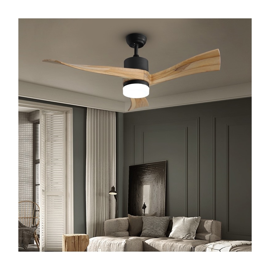 Drevený stropný ventilátor s čiernym krytom a LED osvetlením sa otáča. Je umiestnený v obývacej izbe s pohovkou, závesmi a tmavosivou stenou.