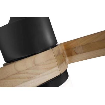 Drevený stropný ventilátor s čiernym krytom sa spája s dreveným ramenom. Spojenie je viditeľné na detailnom zábere.