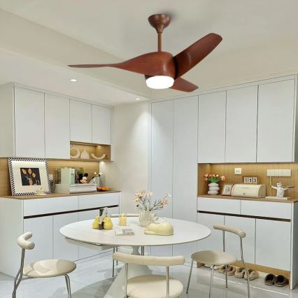 Drevený stropný ventilátor s osvetlením sa otáča v jedálni. Jedáleň má biely nábytok a okrúhly stôl s bielymi stoličkami.
