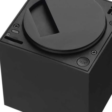 Čierny hranolový prístroj s okrúhlym vrchnákom, na ktorom je umiestnené tlačidlo „reset“. Na boku sa nachádzajú ďalšie malé ovládacie prvky.