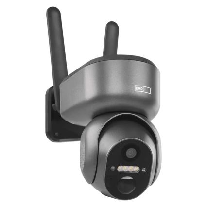 Šedá bezpečnostná kamera s dvomi anténami je pripevnená na stenu. Kamera sníma obraz. Na kamere je nápis „EMOS“.