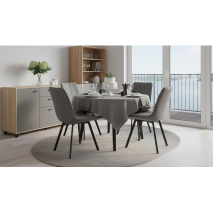 Šedá stolička s čalúnením s prešívaním stojí na štyroch čiernych nohách. Stolička je umiestnená na podlahe s dlaždicami.