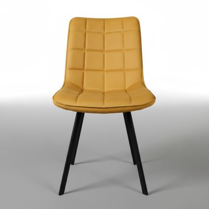 Stolička s čalúneným sedadlom a operadlom v horčicovej farbe a čiernymi kovovými nohami stojí na bielom pozadí.