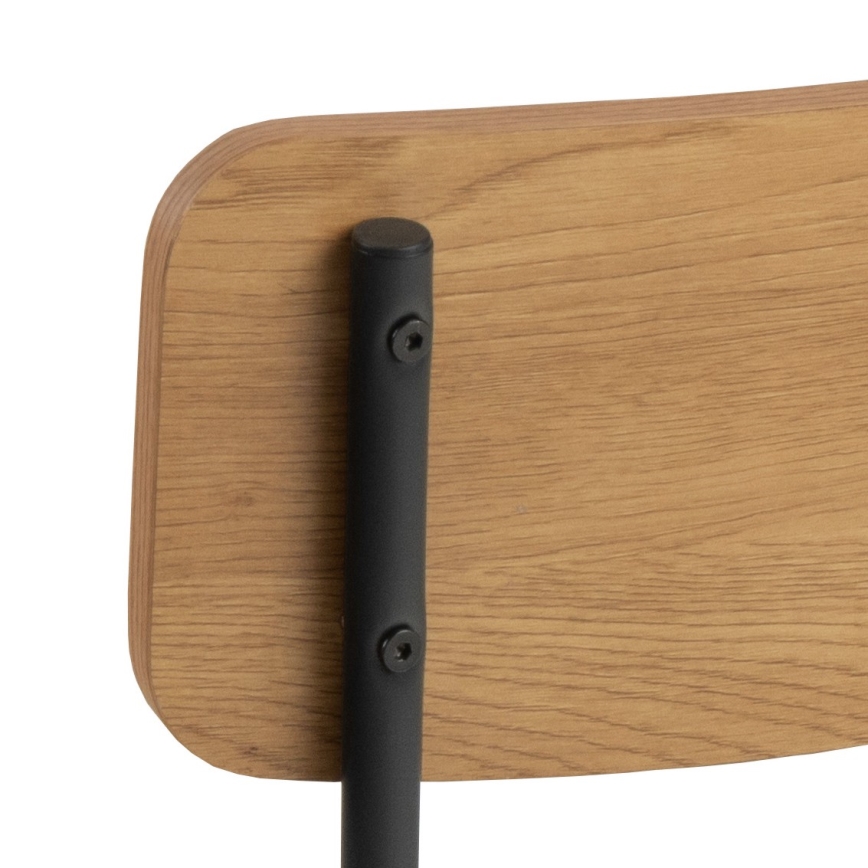 Drevená operadlo stoličky je pripevnené k čiernemu kovovému rámu pomocou skrutiek. Operadlo je svetlohnedej farby s viditeľnou kresbou dreva.