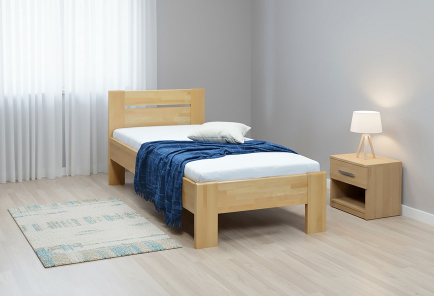 Drevená posteľ s jednoduchým čelom stojí na bielom pozadí. Na posteli je biely matrac, prehodená tmavomodrá deka a svetlý vankúš.