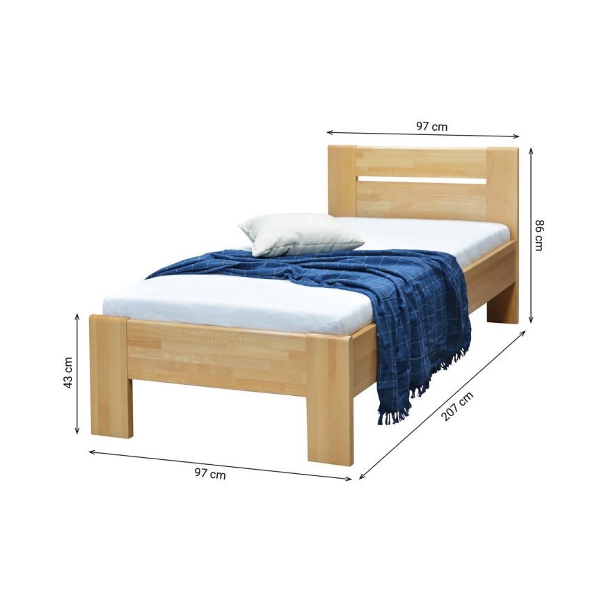 Jednolôžková posteľ z masívneho dreva s rozmermi 97x207x86 cm a výškou nôh 43 cm, je prezlečená bielym matracom a modrou dekou.