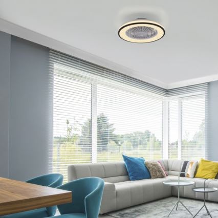 Stropný ventilátor s osvetlením je pripevnený k stropu. Ventilátor je zapustený, v obývacej izbe s rohovou sedačkou, dreveným stolom a oknami s žalúziami.
