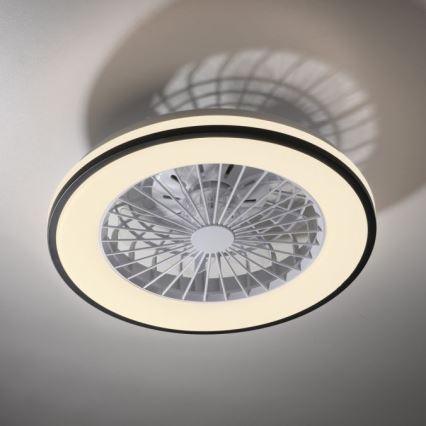 Stropný ventilátor s integrovaným LED osvetlením je pripevnený k stropu. Ventilátor má okrúhly tvar s bielymi lopatkami a svetlým kruhovým LED prstencom. Je umiestnený na svetlom sivom strope.