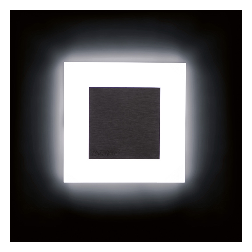 Svietidlo svieti v tmavej miestnosti. Štvorcové svietidlo má tmavosivý stred a biely rámik, ktorý produkuje jasné svetlo. V tmavosivej časti je nenápadne vytlačené logo „Keanox“.