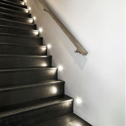 Tmavé drevené schodisko osvetľujú malé vstavané svetlá. Svetlá sú umiestnené pozdĺž steny s dreveným zábradlím.