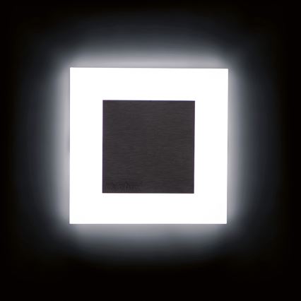 Svietidlo svieti v tmavej miestnosti. Stredový tmavý štvorcový panel je osvetlený väčším bielym štvorcovým rámom. Na tmavom panely je nenápadne vyrazený nápis „KolarZ“.