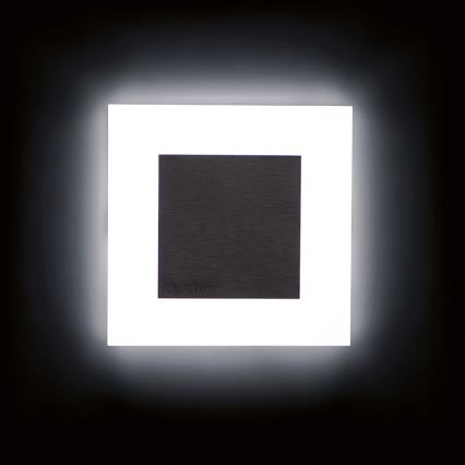 Svietiaca nástenná lampa s tmavosivým stredovým štítkom s nápisom „KranNext“ je osvetlená z vnútornej strany bielym svetlom. Lampa je umiestnená na tmavom pozadí.