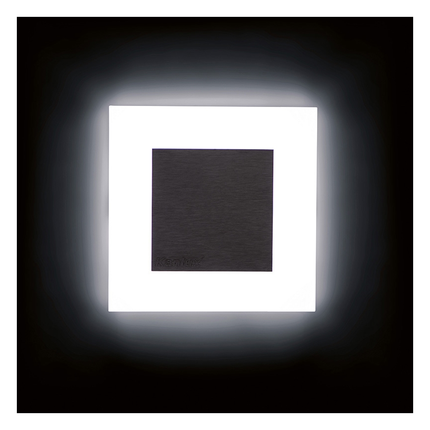 Svietiaca nástenná lampa s tmavosivým stredovým štítkom s nápisom „KranNext“ je osvetlená z vnútornej strany bielym svetlom. Lampa je umiestnená na tmavom pozadí.