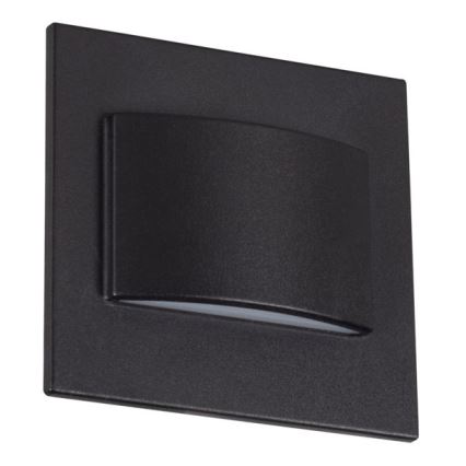 Nástené svietidlo svieti. Je štvorcového tvaru, tmavosivej farby, s mierne prehnutým vnútorným prvkom, ktorý rozptyľuje svetlo. Svietidlo je umiestnené na bielom pozadí.
