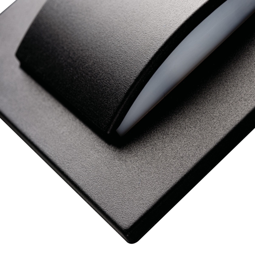 Čierny spínač s mierne zaobleným tlačidlom a jemne zrnitým povrchom je umiestnený na čiernom štvorcovom podklade.