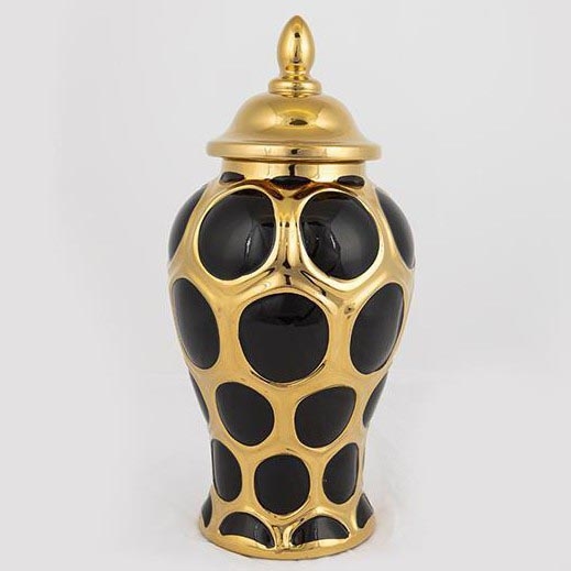 Keramická váza s pokrievkou stojí na bielom podklade. Váza je čierna s veľkými zlatými kruhmi. Pokrievka je zlatá.