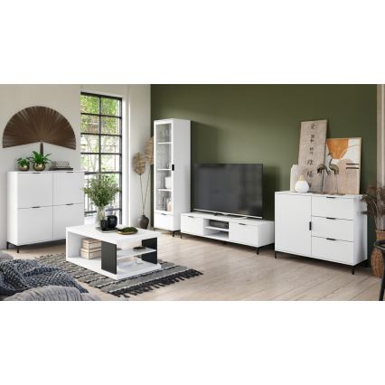 Biely nábytok je umiestnený v obývacej izbe. Súčasťou je televízna zostava, konferenčný stolík, vysoká vitrína a komoda. Nábytok je moderný, s tmavými kovovými nožičkami. Izba má svetlú podlahu a olivovozelenú stenu.