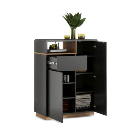 Komoda s otvorenými dvierkami a zásuvkami odhaľuje vnútorné usporiadanie s policami a priehradkami. Je tmavosivá s drevenými prvkami. Na vrchu sú dekoračné predmety.