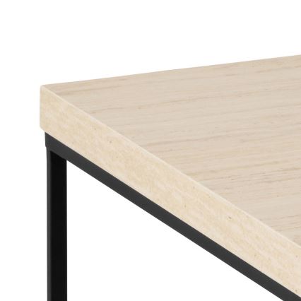 Stolík s béžovou mramorovou doskou a čiernym kovovými nohami stojí na bielom pozadí. Doska je obdĺžniková a nohy sú štíhle a jednoduché.