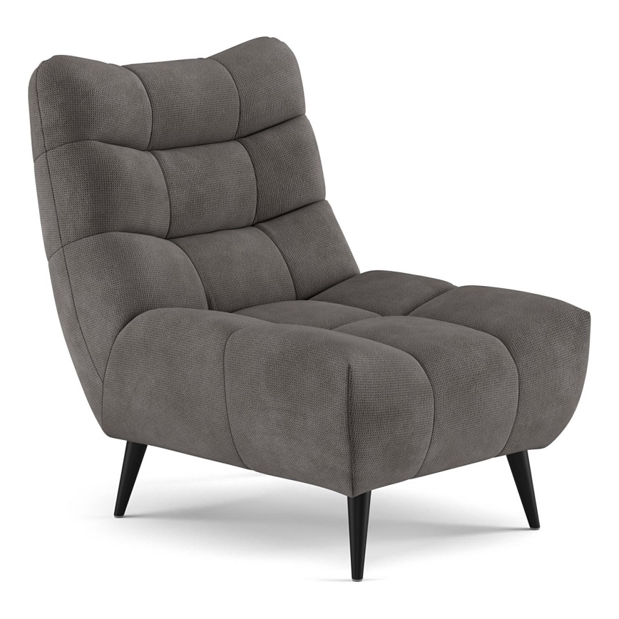 Šedé kreslo s čalúnením v tvare vankúšov stojí na štíhlych čiernych nohách. Nachádza sa na bielom pozadí.