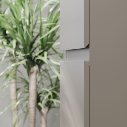 Šedo-hnedá skriňová zostava s integrovanými úchytkami je čiastočne zobrazená na fotografii. V pozadí sa rozostrene nachádzajú izbové rastliny.