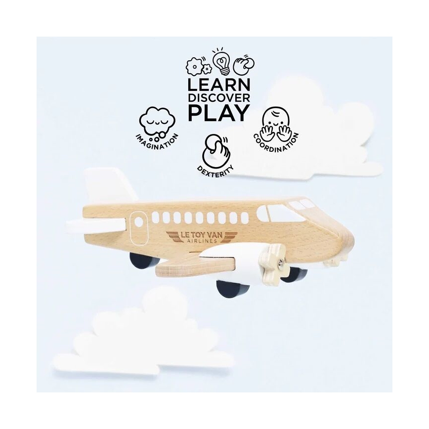 Drevené lietadlo s nápisom „LE TOY VAN AIRLINES“ je umiestnené pred bielymi papierovými mrakmi. Nad lietadlom je text: „LEARN DISCOVER PLAY“, doplnený symbolmi predstavujúcimi predstavivosť, zručnosť a koordináciu.