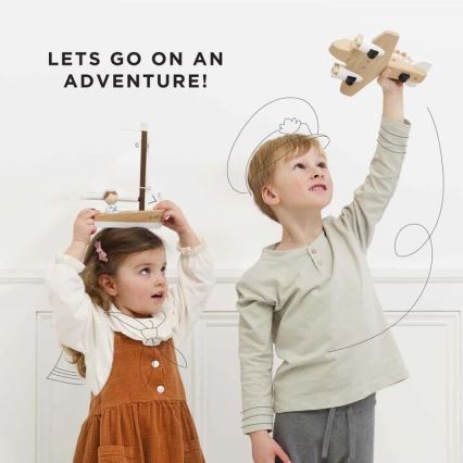Dievča drží drevenú loďku nad hlavou, chlapec drží drevené lietadlo. Obaja deti sa s hračkami hrajú pred bielou stenou. Text na obrázku znie: „LETS GO ON AN ADVENTURE!“.