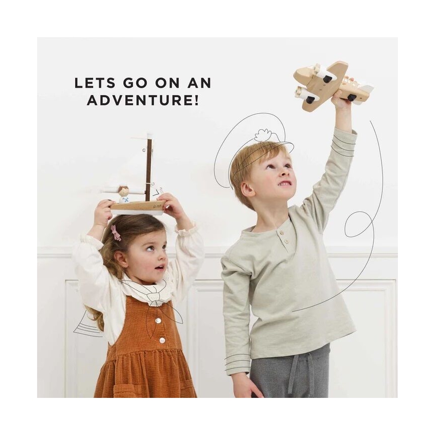 Dievča drží drevenú loďku nad hlavou, chlapec drží drevené lietadlo. Obaja deti sa s hračkami hrajú pred bielou stenou. Text na obrázku znie: „LETS GO ON AN ADVENTURE!“.