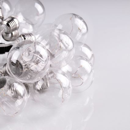 Skupina malých žiaroviek leží na svetlom povrchu. Žiarovky sú spojené, transparentné a vidno vnútorné štruktúry. Sú zložené na sebe.