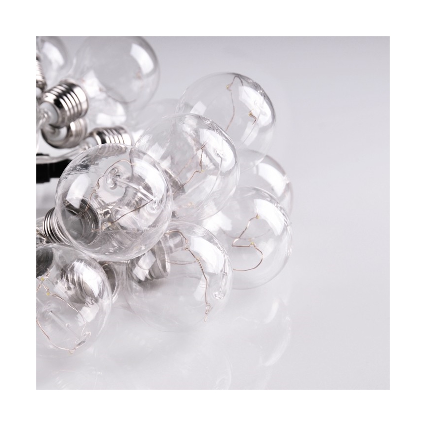 Skupina malých žiaroviek leží na svetlom povrchu. Žiarovky sú spojené, transparentné a vidno vnútorné štruktúry. Sú zložené na sebe.