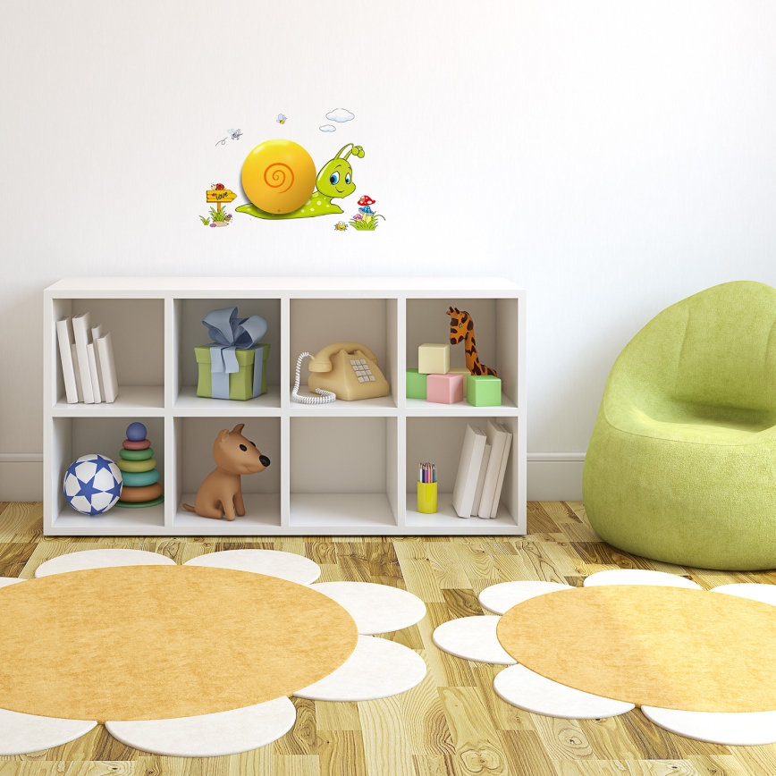 Slimák s ulitou lezie po stene v detskej izbe. Nachádza sa nad bielou policovou zostavou s hračkami a knihami. V izbe je aj zelené kreslo a dva okrúhle koberce v tvare kvetu.
