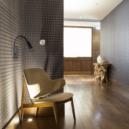 Čierna bodová LED lampa s flexibilným ramenom sa nachádza na bielom pozadí. Lampa je umiestnená v uhle.