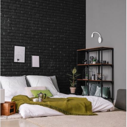 Malá nástenná lampa s ohybným ramenom je pripojená k zásuvke s dvoma otvormi a USB portom. Lampa svieti na šedú plochu.