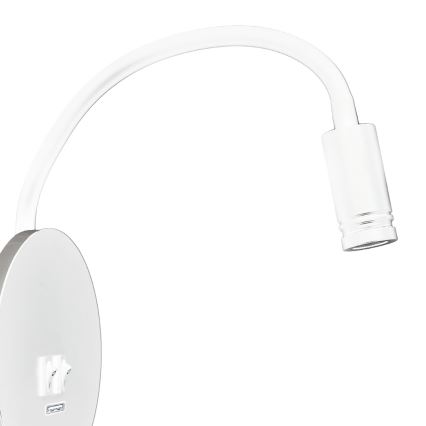 Čierna nástenná lampa s flexibilným ramenom svieti. Lampa je pripojená k okrúhlemu nástennému panelu s dvoma zásuvkami. Panel je umiestnený na tmavosivej stene.