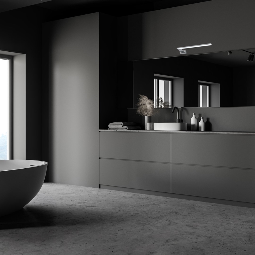 V tmavošedej kúpeľni sa nachádza voľne stojaca oválna vaňa. Šedá skrinka so zabudovaným umývadlom, zrkadlom a osvetlením je umiestnená pri stene. Na umývadle sú kozmetické doplnky.